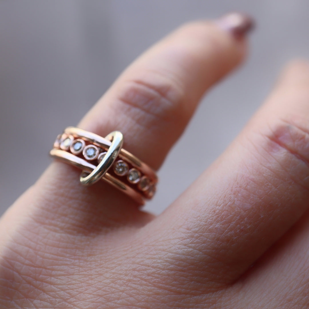 Rose gold ring with diamonds on a finger against a blurred background