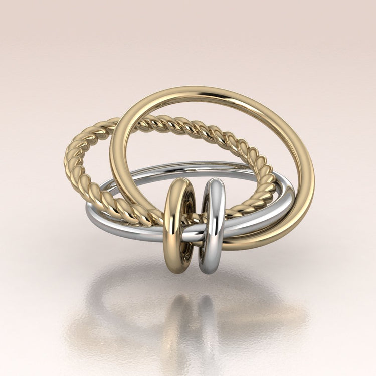 Three gold rings in two tone yellow and white gold stacked on a reflective surface with a light background