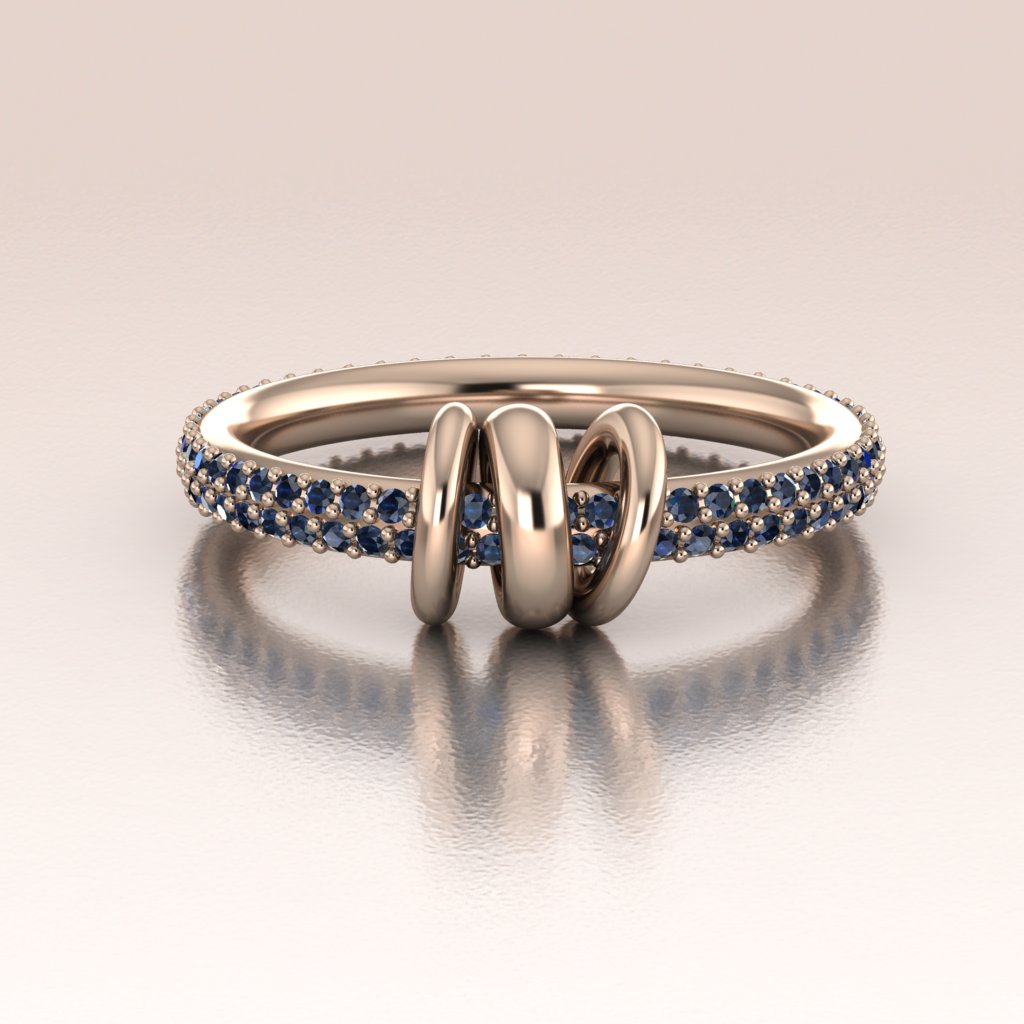 Rose Gold ring with blue sapphires with moving links on a reflective surface