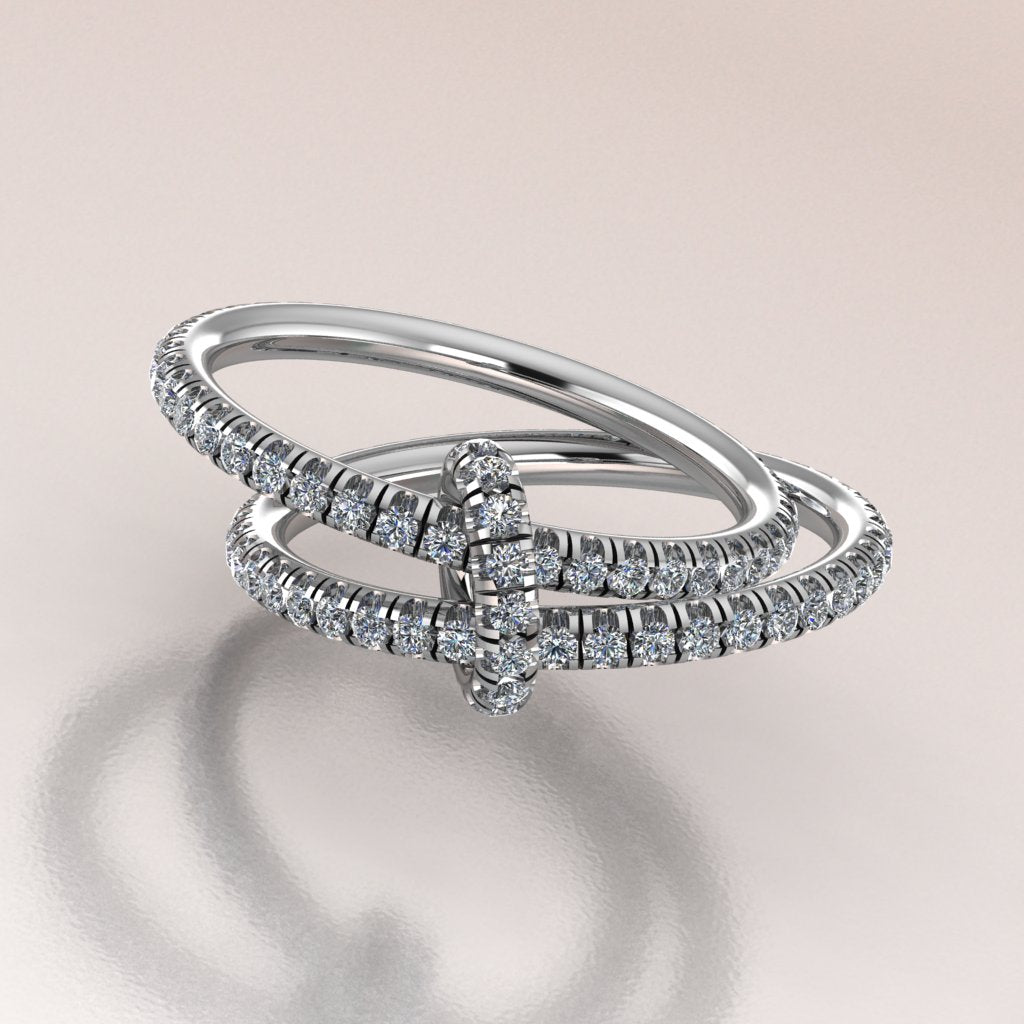 two diamond-studded rings on a reflective surface with a light background