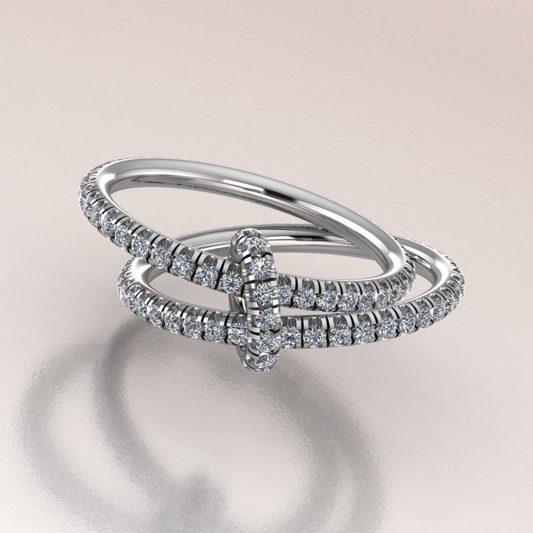 two diamond-studded rings on a reflective surface with a light background