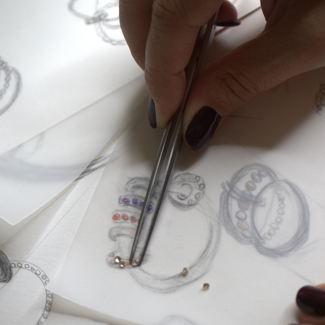 Close-up of hands drawing a custom ring and selecting stones