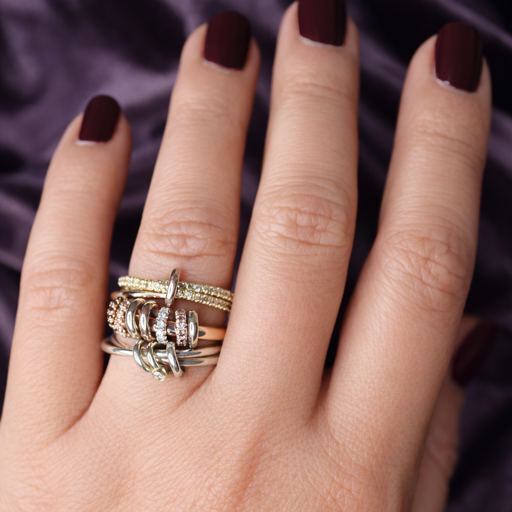 Hand wearing multiple rings with a dark background