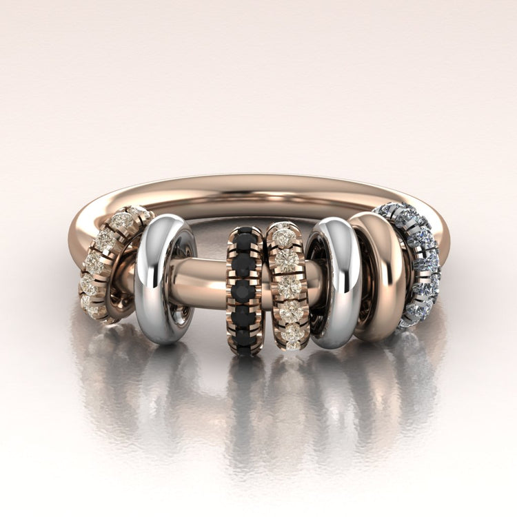 Stack of rose gold and white gold rings with diamond accents on a reflective surface