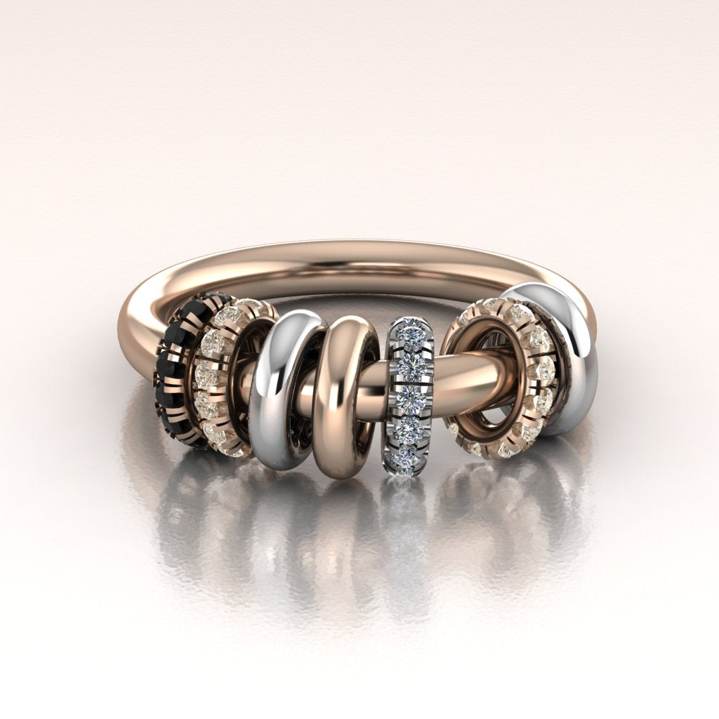 Stack of rose gold and white gold rings with diamonds on a reflective surface with a white background