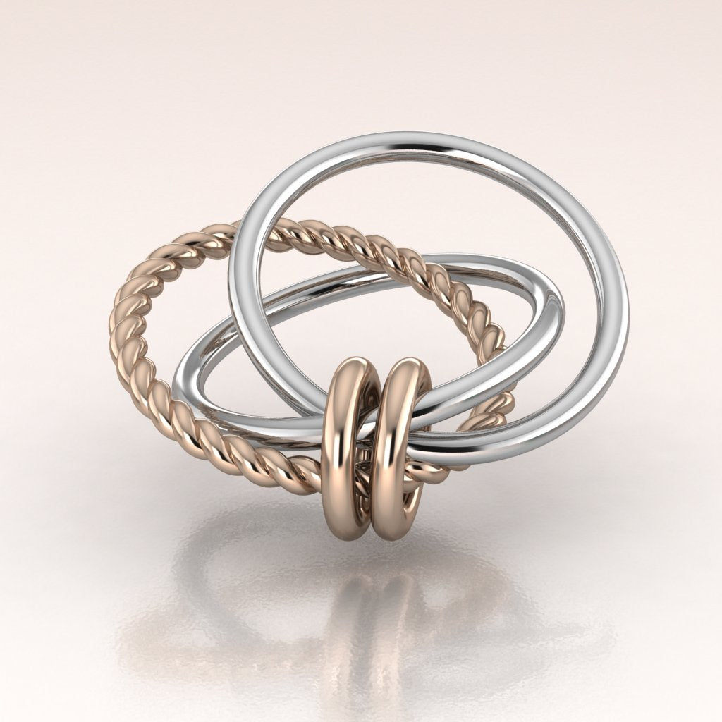 Three interlocking rings in white gold, rose gold on a light background
