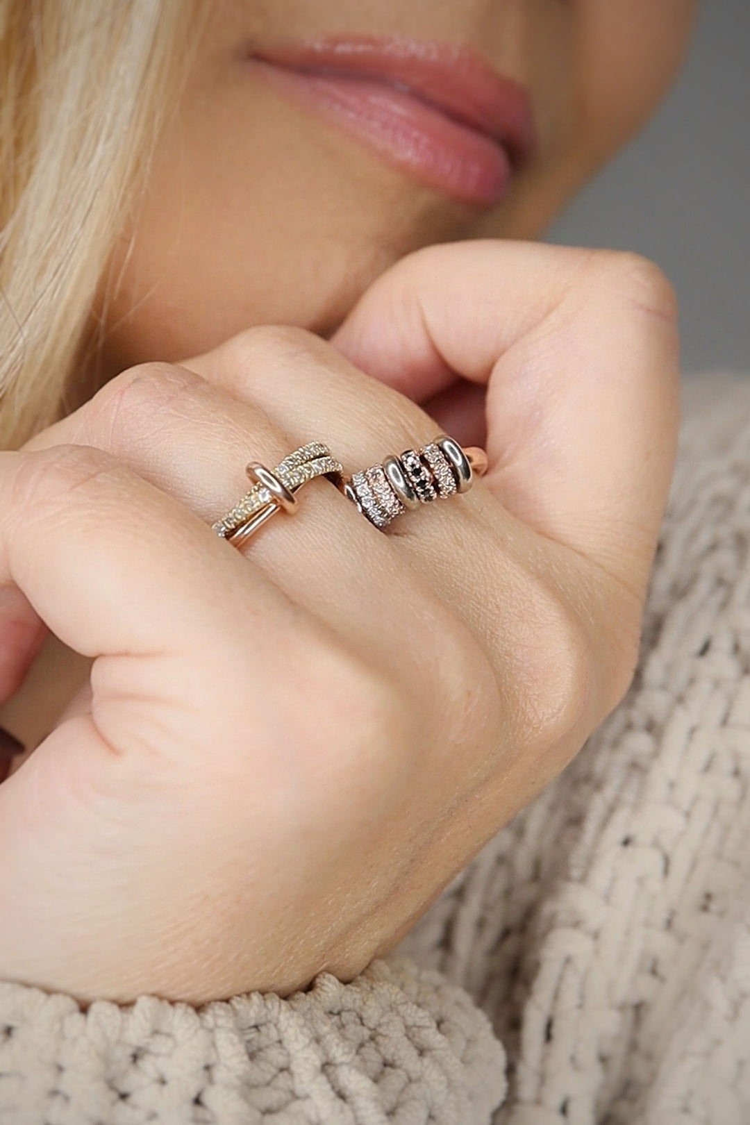 Close-up of a hand wearing two rings on a neutral background